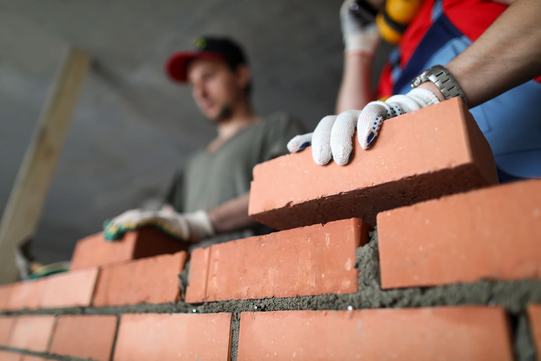 Two Surrey masons laying red brick together