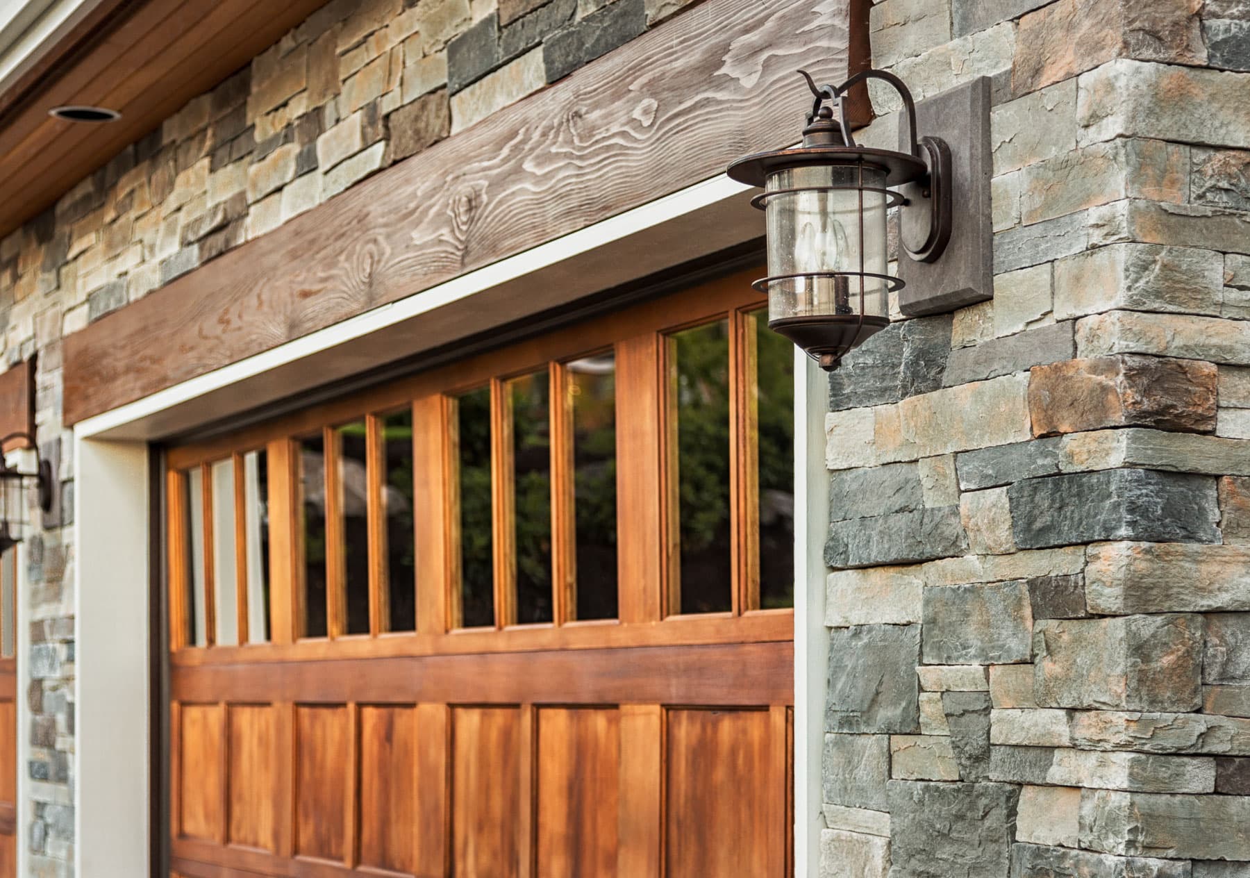 Natural stone veneer on a Surrey home exterior beside a wood garage door