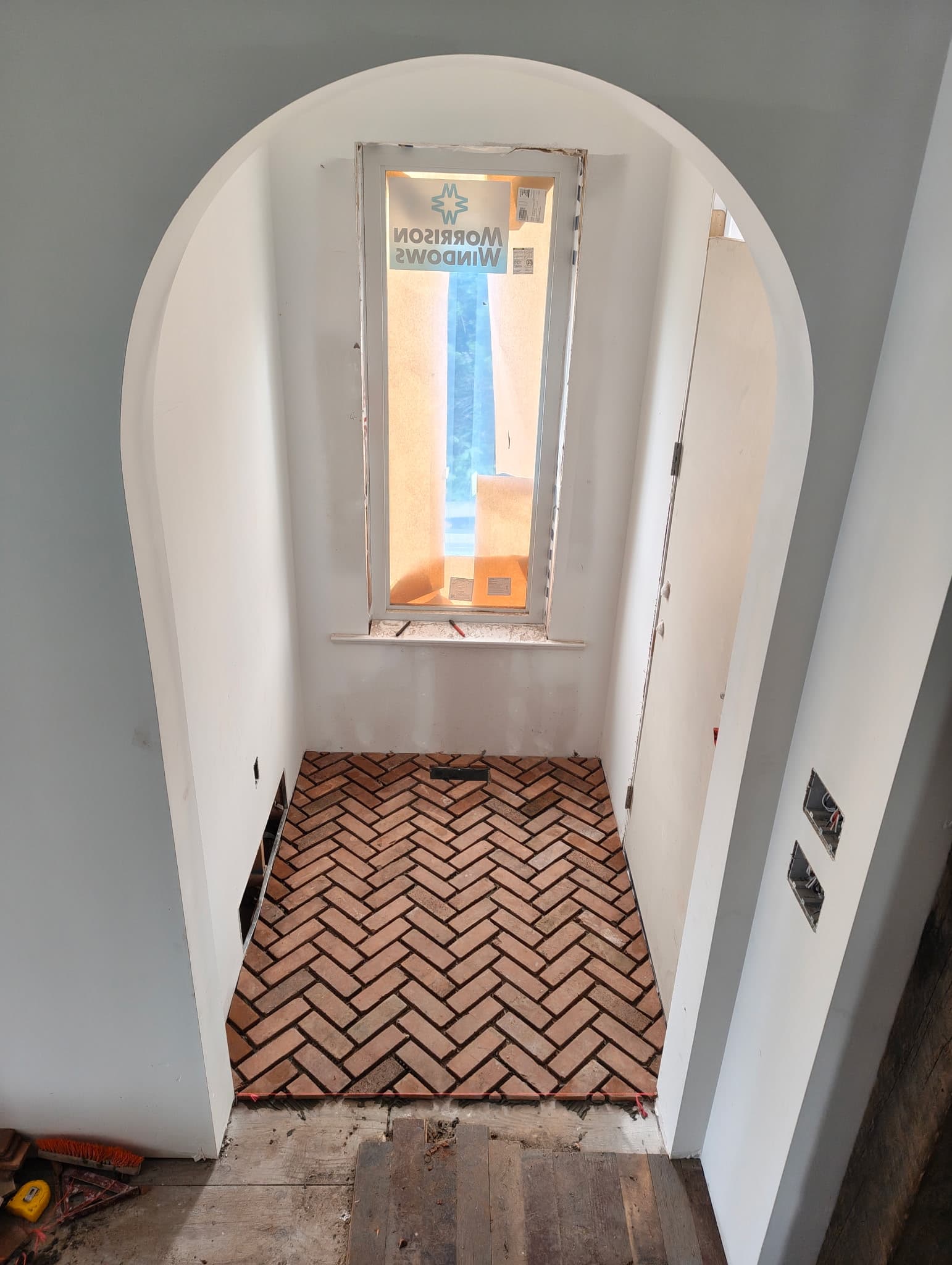 Herringbone brick flooring laid in an arched entry alcove