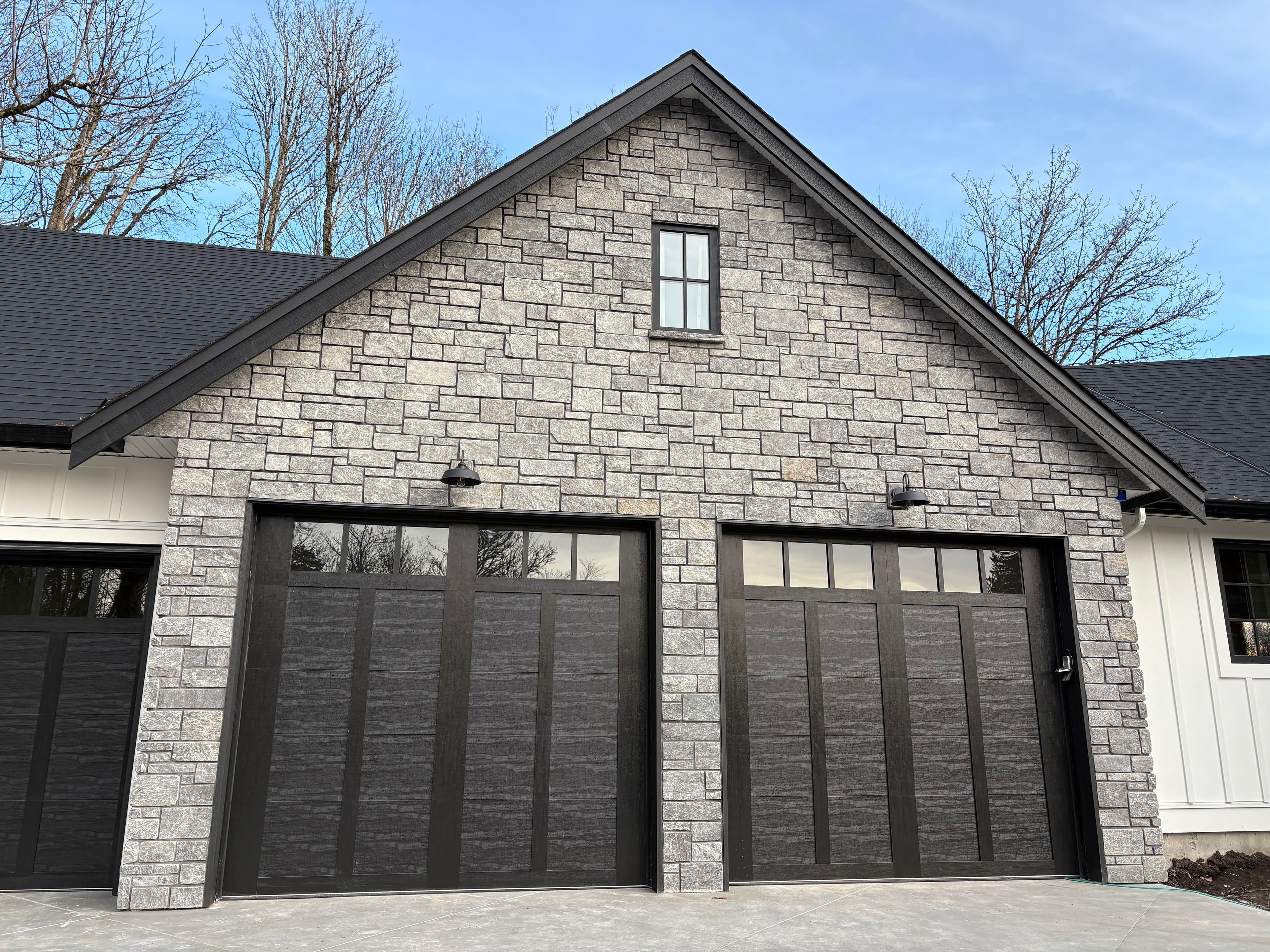 Grey stone veneer garage facade with stacked stone and gabled peak