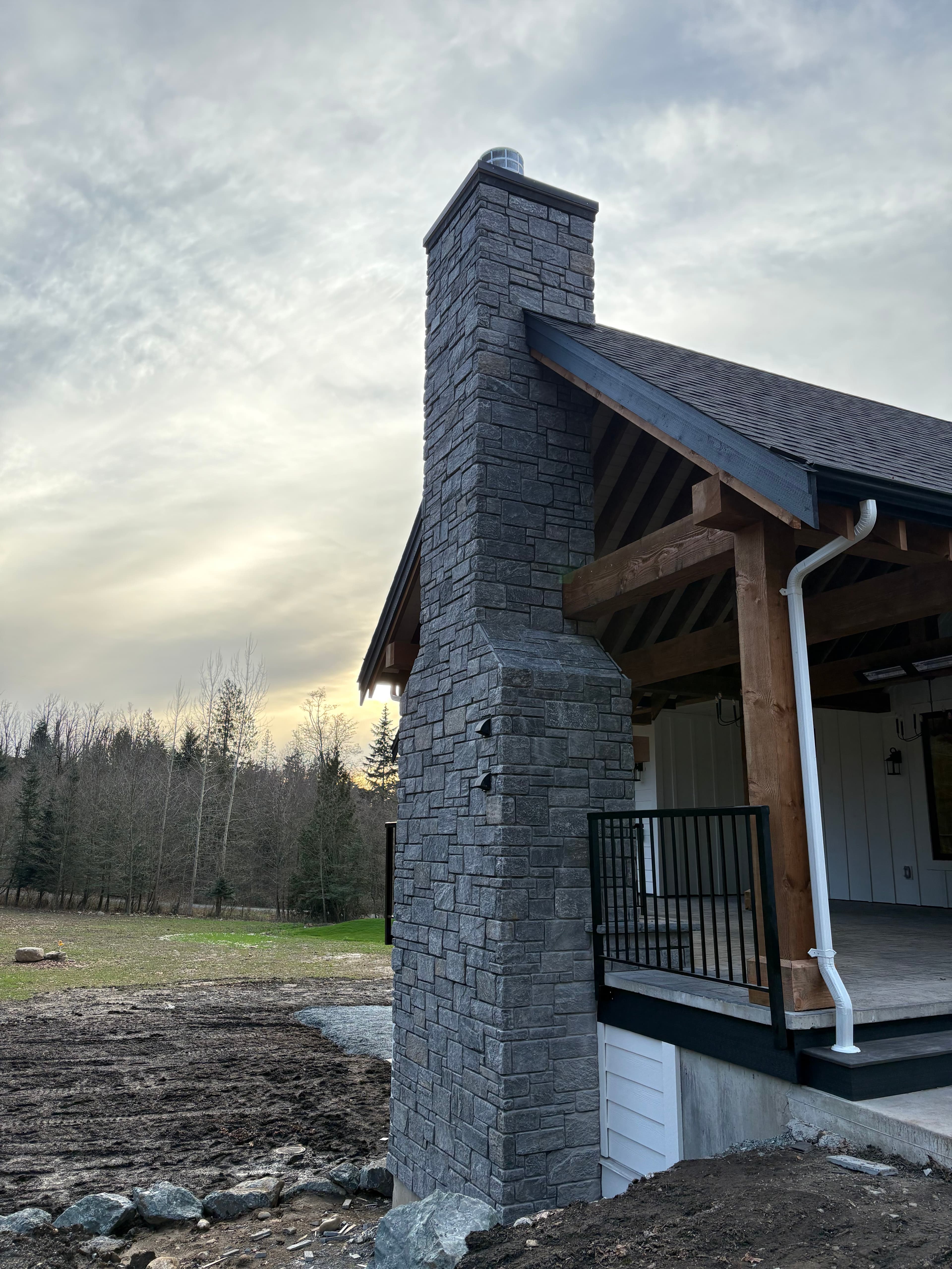 Grey stone veneer chimney and column on a timber-frame covered porch