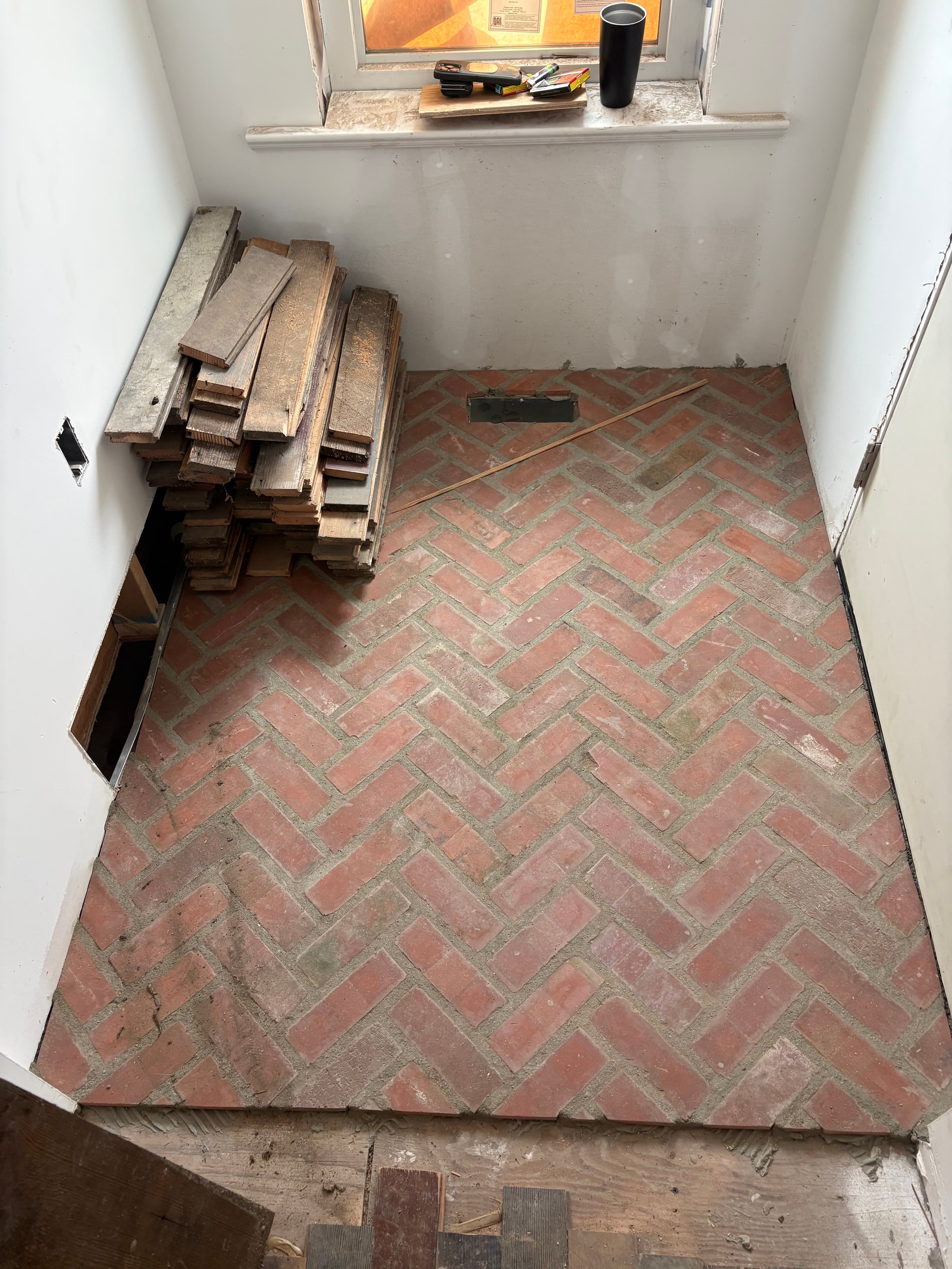 Red herringbone brick floor being installed in a mudroom