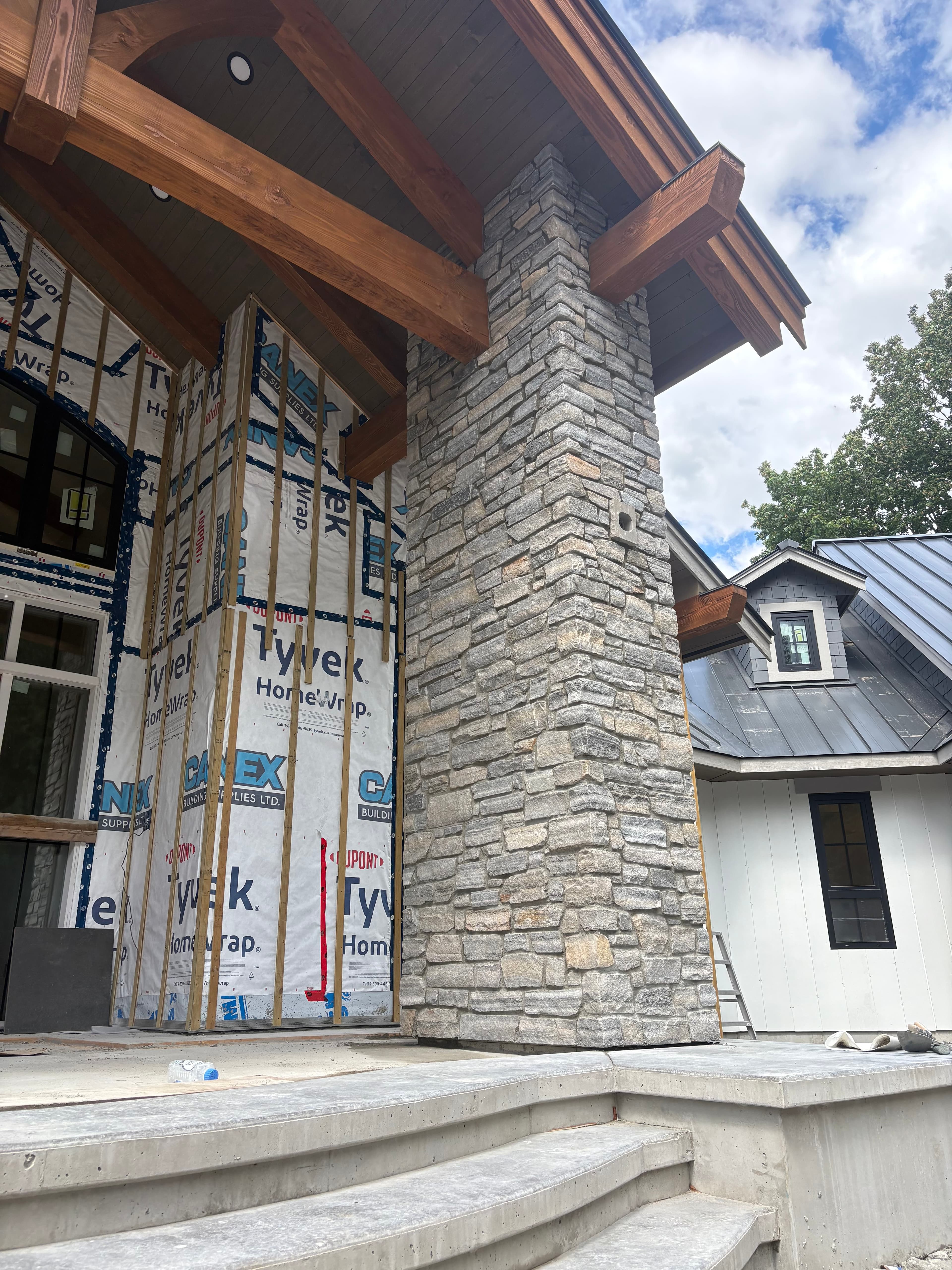 Stacked grey stone veneer column and chimney on a custom build