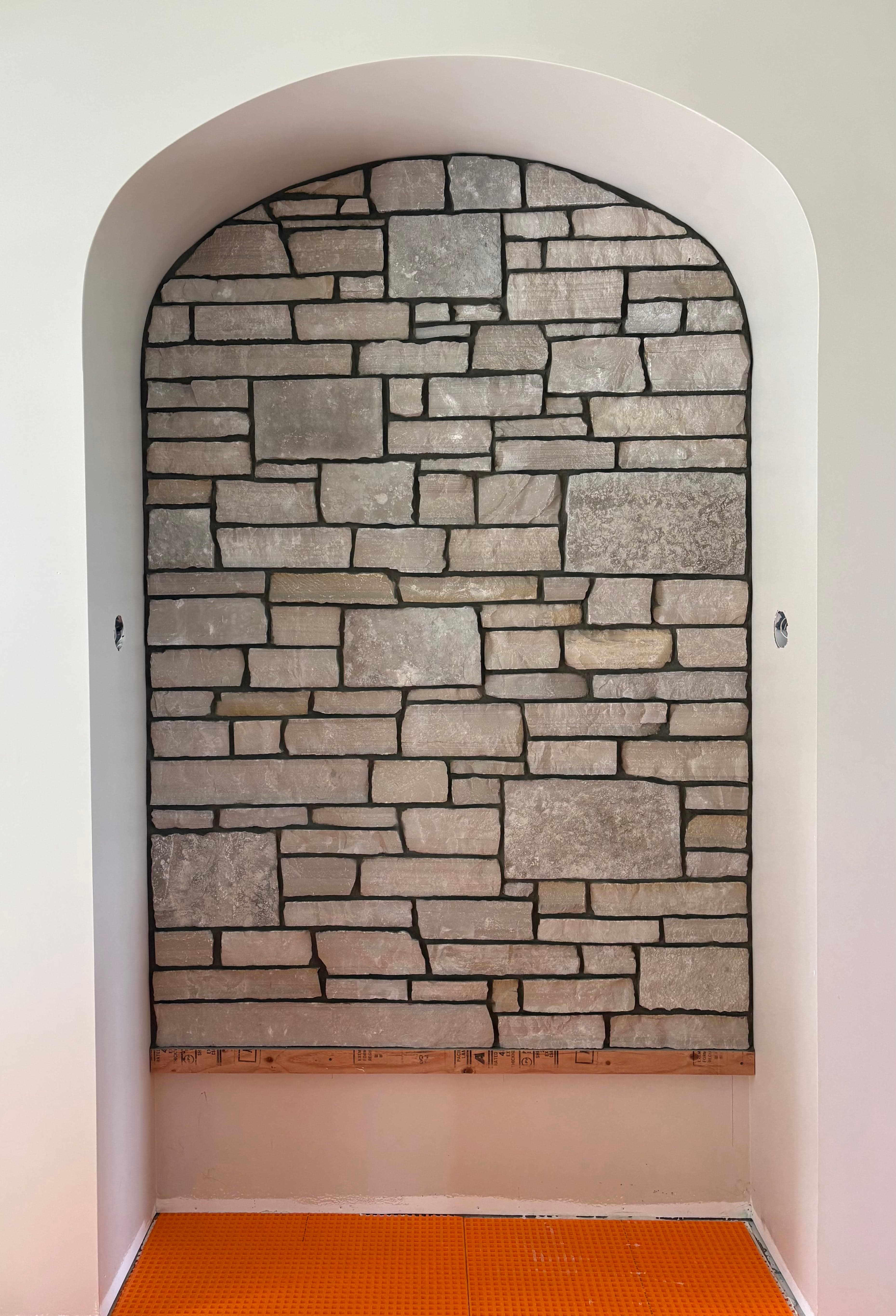 Light natural stone feature wall set into an arched interior niche