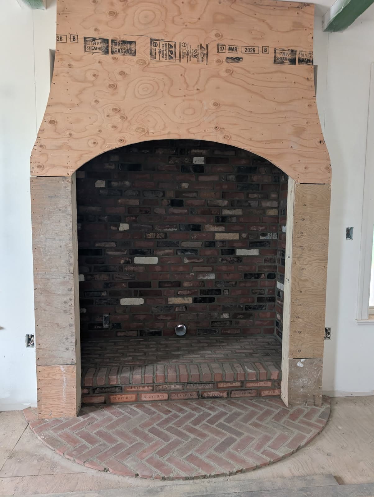 Brick fireplace firebox with herringbone brick hearth under construction
