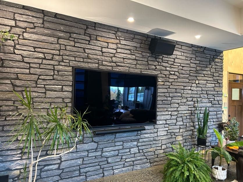 Stacked grey stone veneer interior feature wall with mounted television