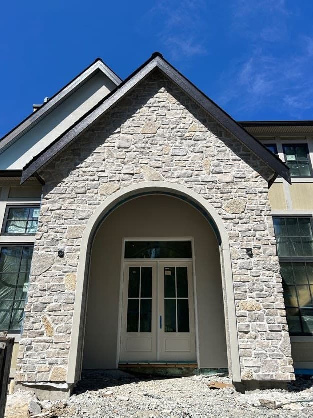 Cream natural stone veneer on an arched front entry and gable