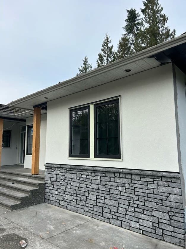 Grey stacked stone veneer wainscot against white stucco exterior